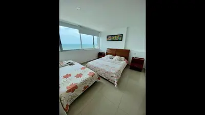 a bedroom with two beds and a window with the ocean at 2 Bedroom Beachfront Apartment 2P1-Al With Pool And WIFI in Cartagena de Indias