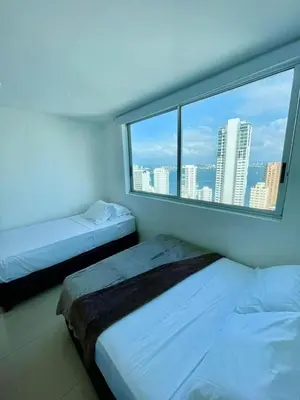 two beds in a room with a large window at 2 Bedroom Beachfront Apartment 2P1-Al With Pool And WIFI in Cartagena de Indias