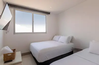 two beds in a small room with a window at Laurdhomes Palmetto Beach Floor 32, Sea View, 3HBT in Cartagena de Indias
