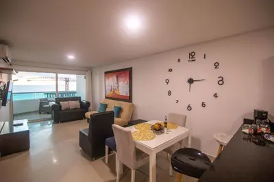 a living room with a table and a clock on the wall at 2B/2B Gorgeous Sunsets-Ocean View -Pool in Cartagena de Indias