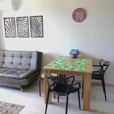 a table and chairs in a living room with a clock at Cómodo apartamento cerca al mar. in Cartagena de Indias
