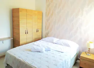 a bedroom with a white bed with a wooden cabinet at Cómodo apartamento cerca al mar. in Cartagena de Indias