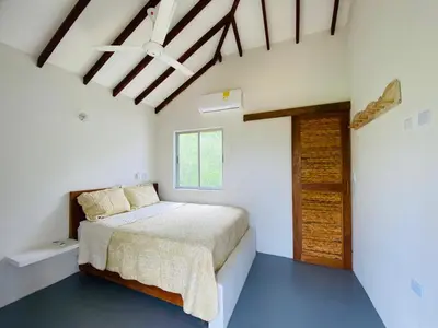 a white bedroom with a bed and a window at Cabaña cerca al Mar con Pisicina y AC en Tolú in Tolú