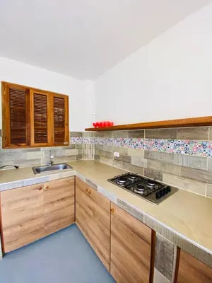 a kitchen with wooden cabinets and a stove top oven at Cabaña cerca al Mar con Pisicina y AC en Tolú in Tolú
