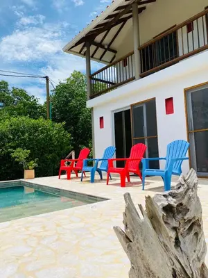 a group of red and blue chairs next to a pool at Cabaña cerca al Mar con Pisicina y AC en Tolú in Tolú