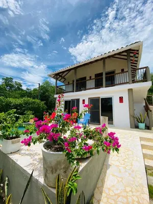 a house with some flowers in front of it at Cabaña cerca al Mar con Pisicina y AC en Tolú in Tolú