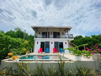a house with a pool and red chairs at Cabaña cerca al Mar con Pisicina y AC en Tolú in Tolú