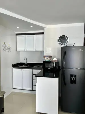 a kitchen with a black refrigerator and white cabinets at Relax y Confort - Apartamento frente al Mar in Cartagena de Indias