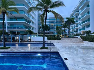 a swimming pool with palm trees in front of a building at DISFRUTE Y PLAYA in Cartagena de Indias
