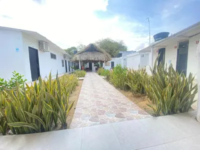 a walkway leading to a building with a thatch roof at Hostal El Danubio Tolu in Tolú