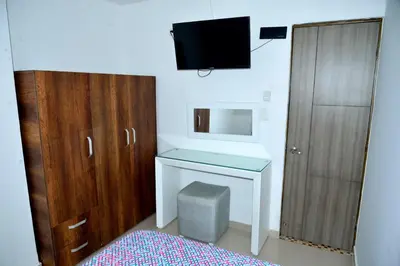a bedroom with a bed and a desk and a tv at Edificio Cristoforo Colombo Apartamento in Cartagena de Indias