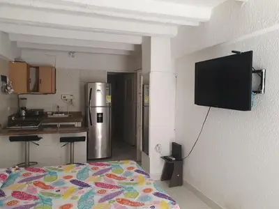 a kitchen with a refrigerator and a tv on a wall at @casa__grace Apartaestudio en edificio al frente del mar!! in Cartagena de Indias