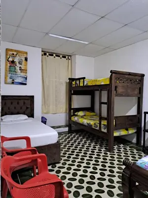 a room with two bunk beds and a red chair at Hostal Casa Lara in Cartagena de Indias