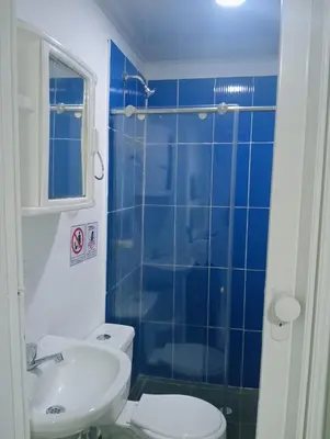 a blue tiled bathroom with a toilet and a sink at Hostel HA LUXURY in Cartagena de Indias