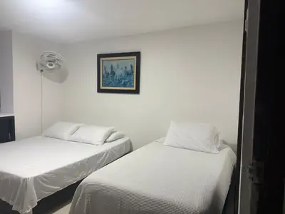 a bedroom with two beds and a picture on the wall at Lindos apartamentos in Cartagena de Indias