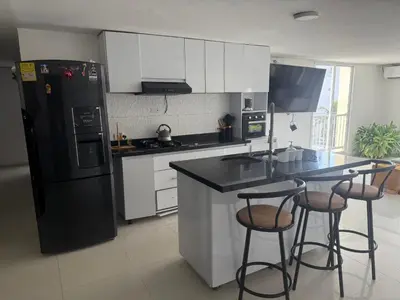 a kitchen with a black refrigerator and two bar stools at Lindos apartamentos in Cartagena de Indias