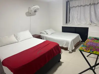 a room with two beds and a table and a window at Lindos apartamentos in Cartagena de Indias