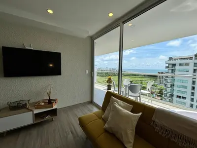 a bedroom with a couch and a large window at Dominiqueplayaazul apto de lujo con Jacuzzi privado en balcon in Cartagena de Indias
