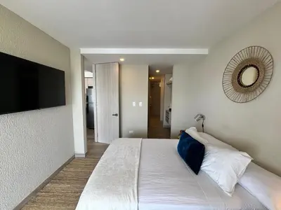 a bedroom with a large bed and a flat screen tv at Dominiqueplayaazul apto de lujo con Jacuzzi privado en balcon in Cartagena de Indias