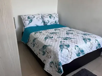 a bed with a blue and white blanket and pillows at Vista a la Playa del Cabrero in Cartagena de Indias