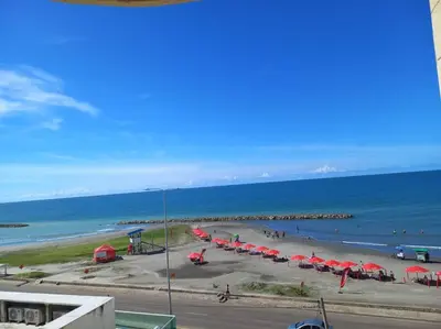 a beach with red umbrellas and the ocean at Vista a la Playa del Cabrero in Cartagena de Indias