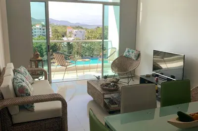a living room with a table and chairs and a pool at * * Magnífico * * apto en la playa * *Costazul 405 in Santa Marta