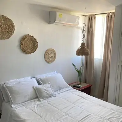 a bed with white sheets and pillows in a bedroom at Habitación en apartamento compartido al frente del cc Unico in Barranquilla