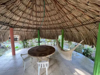 a table and chairs under a thatched umbrella at Casa Santa María in El Porvenir