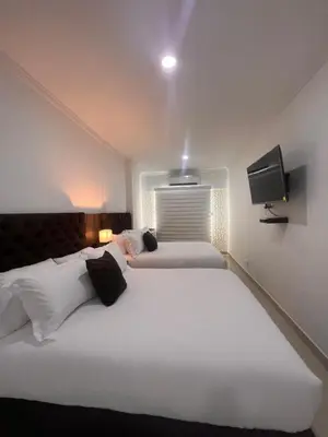 two beds in a hotel room with a tv on the wall at Hotel Zuriel Boutique in Cartagena de Indias