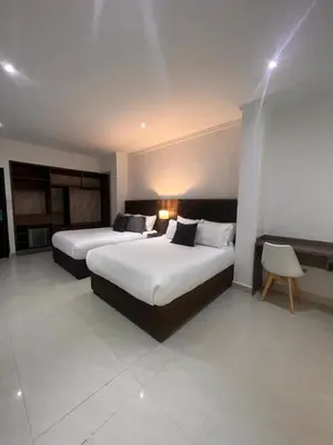 a hotel room with two beds and a chair at Hotel Zuriel Boutique in Cartagena de Indias