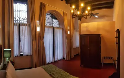 a bedroom with a bed and a chandelier and windows at Hotel Boutique Casa Córdoba Estrella in Cartagena de Indias