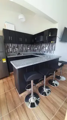 a kitchen with a black counter and bar stools at Apto en Coveñas cerca al mar in Coveñas