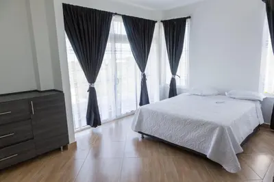 a bedroom with a bed and a dresser and large windows at Beach cabin near Barranquilla in Santa Veronica
