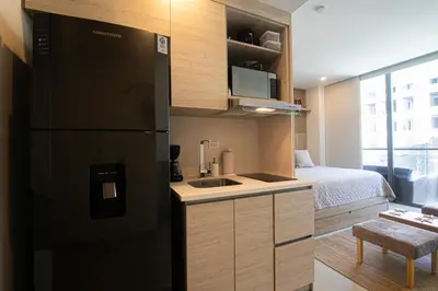 a small kitchen with a black refrigerator and a bed at Apartamento en Condominio con acceso directo al mar en Cartagena in Cartagena de Indias