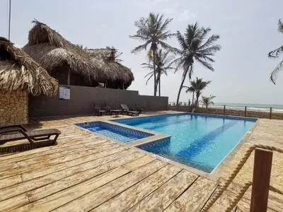 a swimming pool next to a resort with palm trees at Dúplex de lujo con vista al mar - San Bernardo del Viento in San Bernardo del Viento