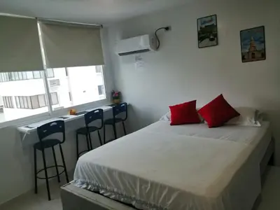 a bedroom with a bed with red pillows and a bar at Estudio tipo Loft Amoblado en Bocagrande Cartagena 801A in Cartagena de Indias