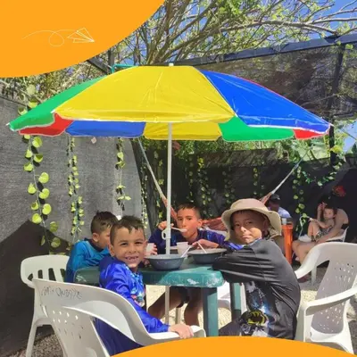 a group of children sitting at a table under an umbrella at HOTEL HERMOSO CARIBE in Tolú