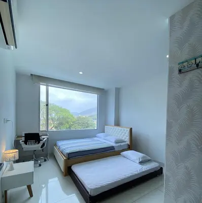 two beds in a room with a window at Hermoso Apto Familiar en sector Bello Horizonte in Santa Marta