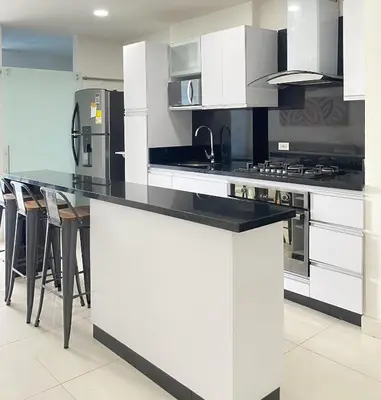 a kitchen with white cabinets and a black counter top at Hermoso Apto Familiar en sector Bello Horizonte in Santa Marta