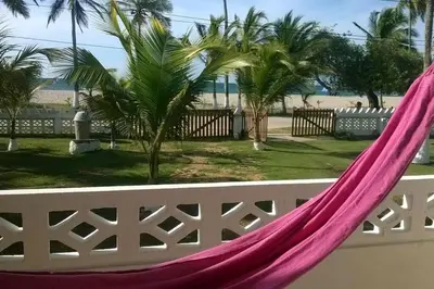 a pink hammock on a white fence with palm trees at Apartamento frente al mar mejor playa en Coveñas in Coveñas