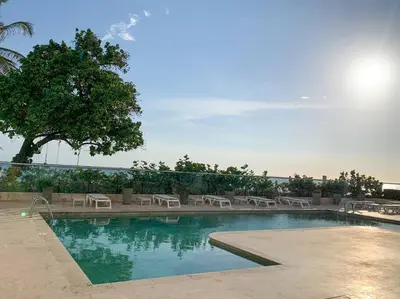 a swimming pool with chairs and a tree in the background at Sea, Sand & Skyline 30th-Floor Poolside Getaway in Cartagena de Indias