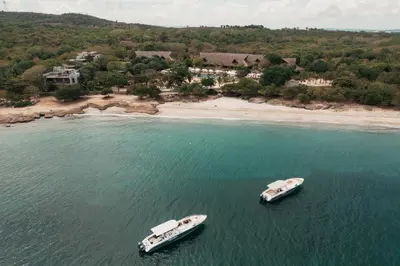 two boats in the water next to a beach at Makani Luxury Cartagena in Tierra Bomba