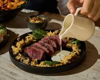 a person pouring sauce on a plate of food at Makani Luxury Cartagena in Tierra Bomba