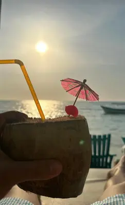a person holding a drink with an umbrella on the beach at Tequila SunBeach Baru Eco-Hotel in Baru