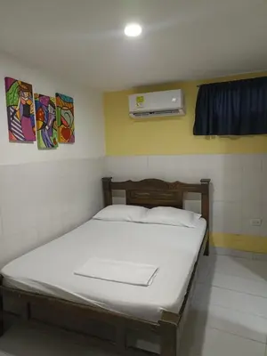 a bedroom with a bed with a white bedsheet and a window at HOSTAL EL ALTISIMO in Cartagena de Indias