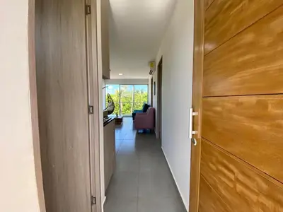 a hallway with a wooden door and a chair at NAHIR apartamento de playa en condominio Palmar del viento in San Bernardo del Viento