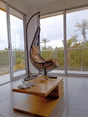 a wicker swing sitting on a table in a room with windows at NAHIR apartamento de playa en condominio Palmar del viento in San Bernardo del Viento