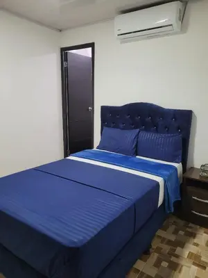 a blue bed in a white room with a blue bedspread at Apartahotel Los Ángeles in Cartagena de Indias