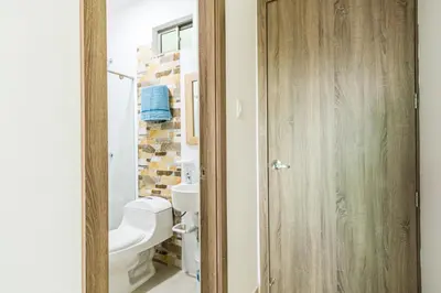 a bathroom with a toilet and a wooden door at Makadamia Aptos in Sincelejo