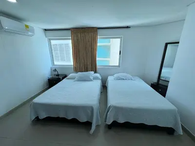 two beds in a room with two windows at Apartamento en Laguito Ed Torres del Lago 604 ICDI in Cartagena de Indias